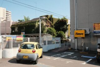 Yellow car in an urban Japan parking lot with ivy-covered building.