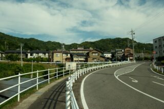Curved road through suburban Gamagōri, Japan, with traditional houses and lush hills.