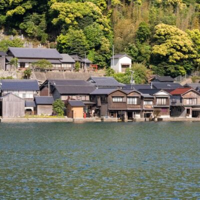 Idyllic waterfront houses in Ine, Kyoto, Japan with lush greenery.