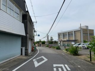 A tranquil suburban street in Osaka, Japan, featuring urban architecture and parked cars.