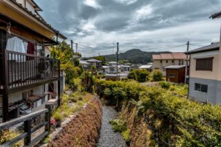 Charming Japanese townscape on a cloudy day with lush greenery and traditional houses.