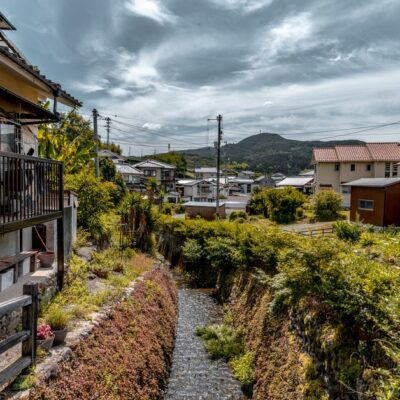 Charming Japanese townscape on a cloudy day with lush greenery and traditional houses.