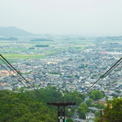 Picturesque scenery of rope way cable against contemporary city situated on vast hilly valley on clear day